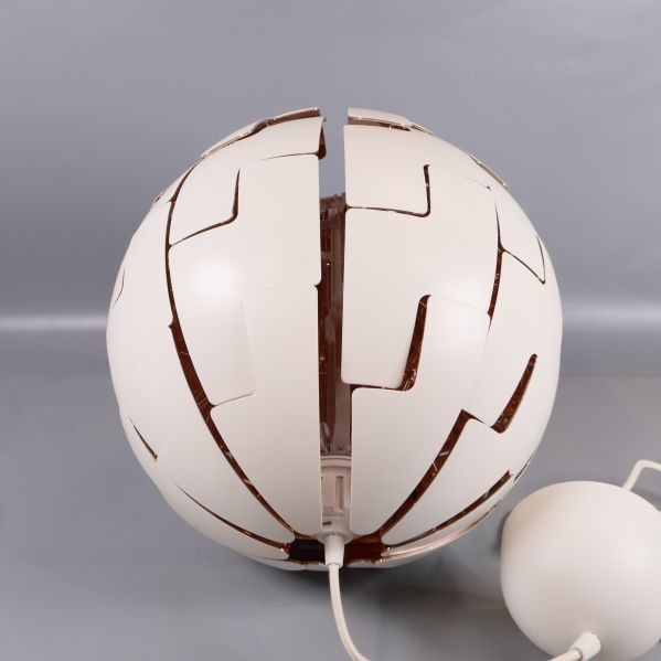 Närbild på lampa med öppning i mitten och vit kopparfärgad design