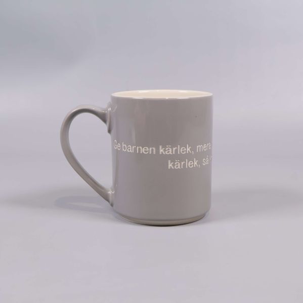 Grå mugg med vitt tryckt citat och handtag till vänster