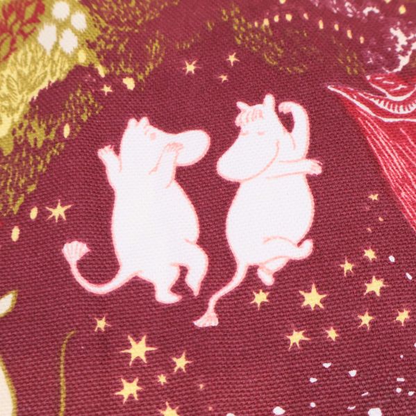 Två muminfigurer dansar bland stjärnor på röd textil
