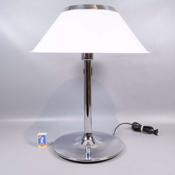 Vit bordslampa med metallfot och synligt vägguttag