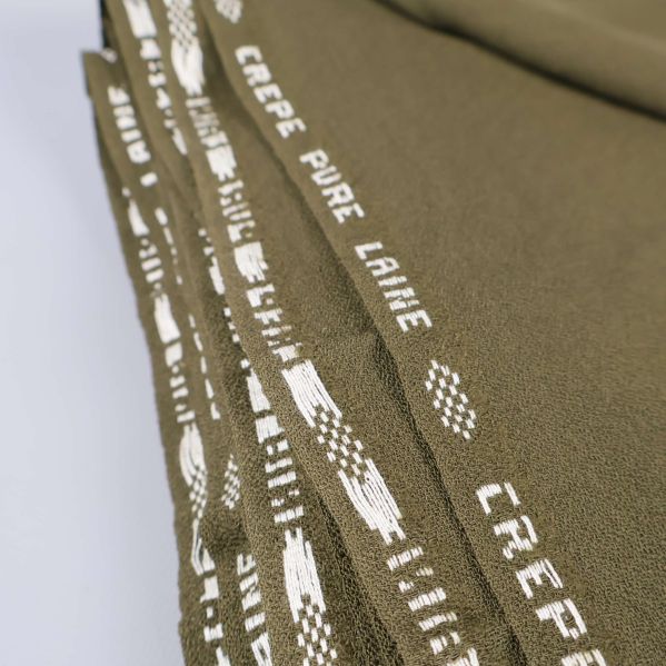 Närbild på texten 'Crepe Pure Laine' på tygkant