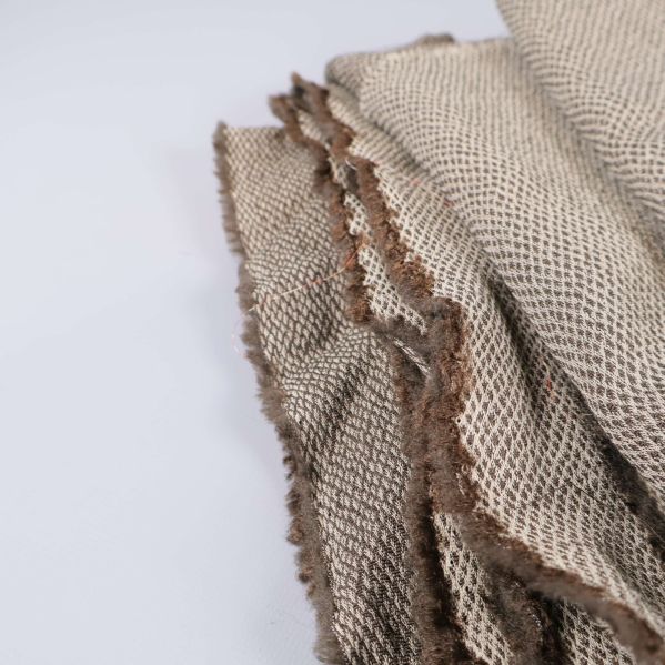 Rå kant av beige vävt tyg i närbild