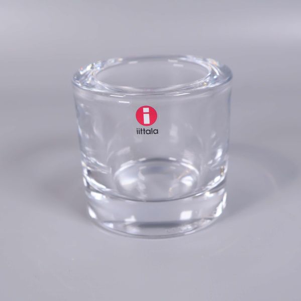 En ljushållare i glas med rött Iittala-klistermärke