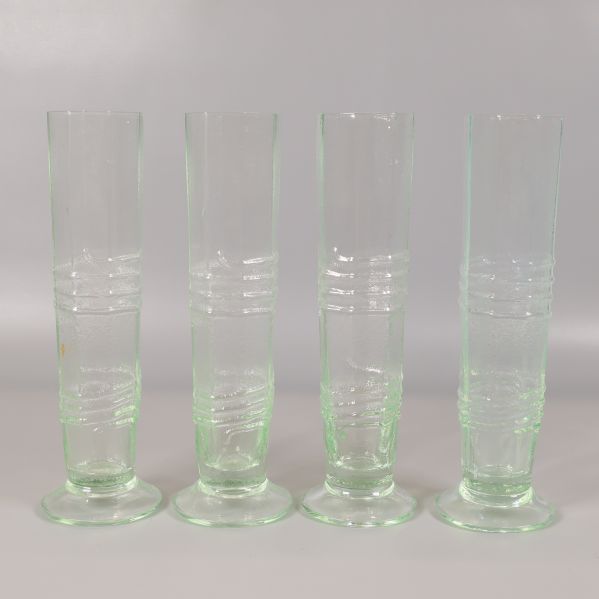 Fyra höga ljusgröna glas med räfflat mönster stående på rad