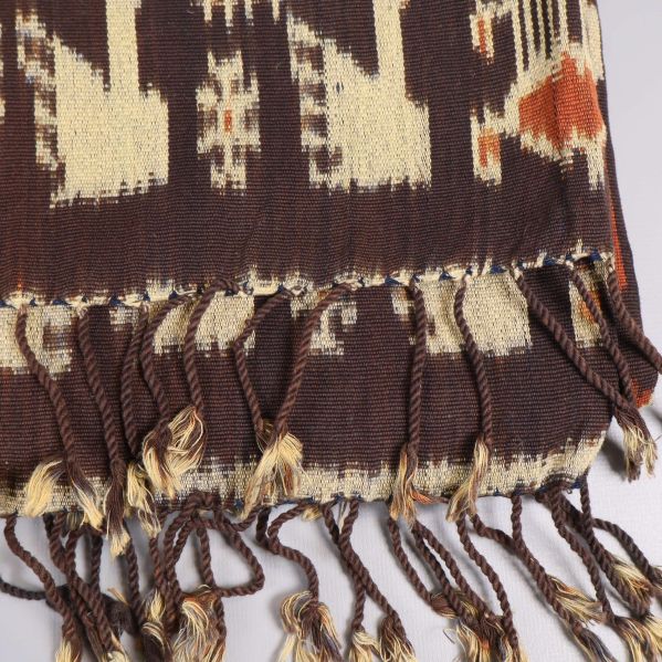 Fransad kant på brunmönstrad textil i närbild