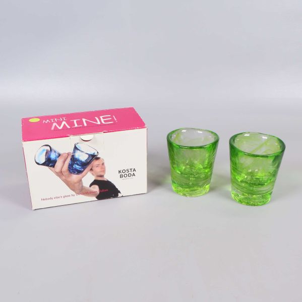 Två gröna snapsglas och originalförpackning mot ljus bakgrund