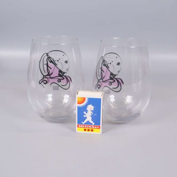 Två glas med motiv bredvid tändsticksask