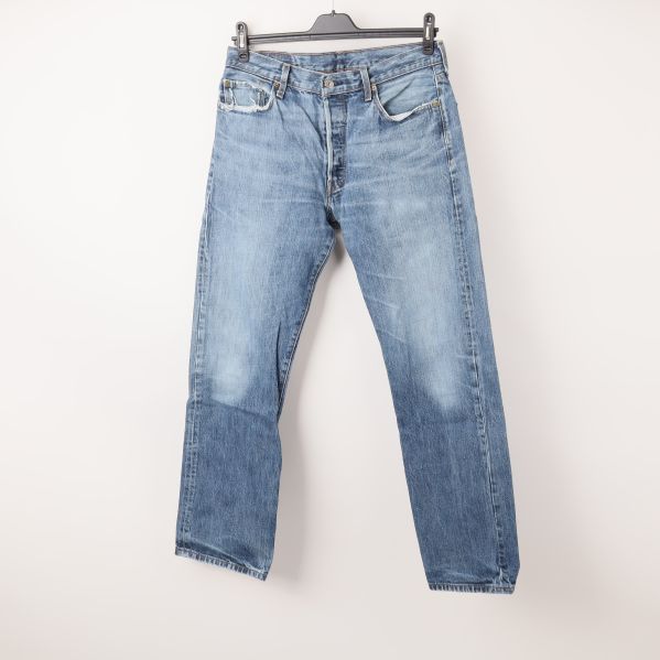 Framsidan av blå jeans med knappgylf och fickor