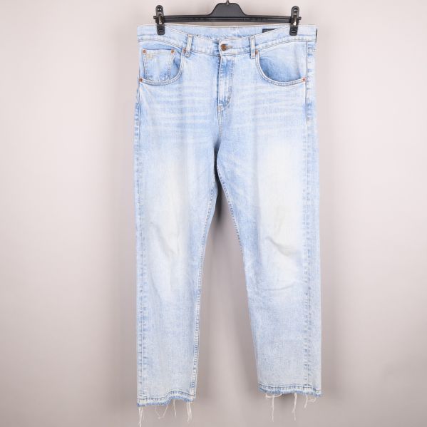 Framsida av ljusa jeans med rå fåll