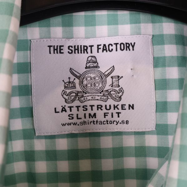 Etikett 'The Shirt Factory' på rutigt tyg