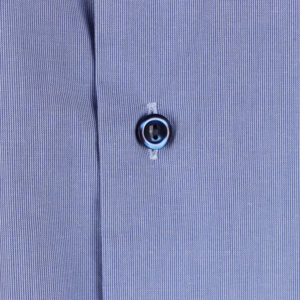 Närbild på skjortknapp på ljusblå tyg