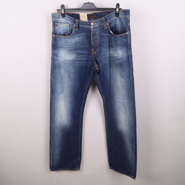 Framsida av mörkblå jeans med slitningar