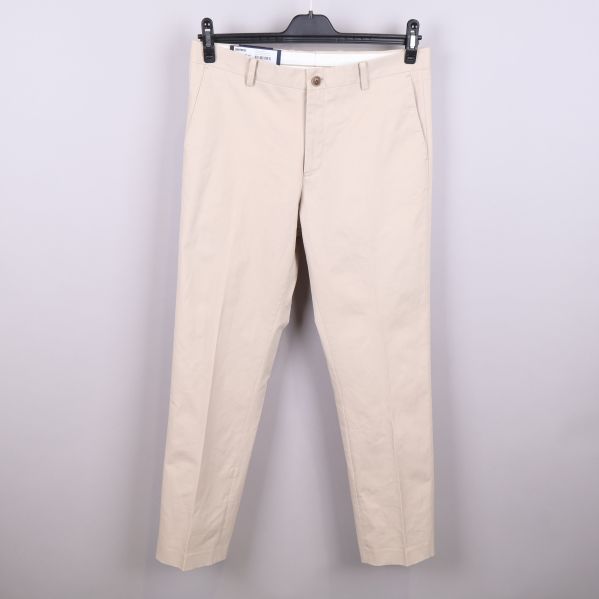 Framsidan av beige chinos med knapp