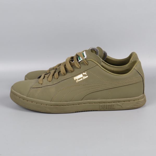 Sidovy av sneaker med guldtext och olivgrön sula