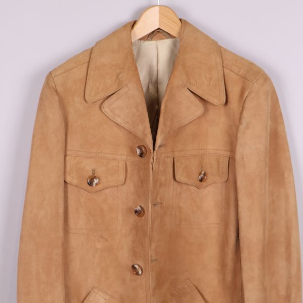 Närbild av överdelen med kragar och fickor på beige mockajacka