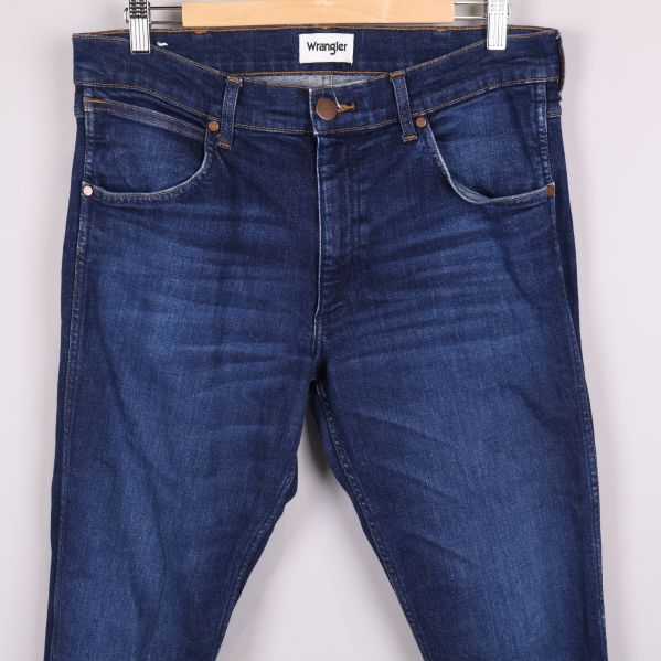 Närbild framtill på jeans med tydliga fickor och sömmar