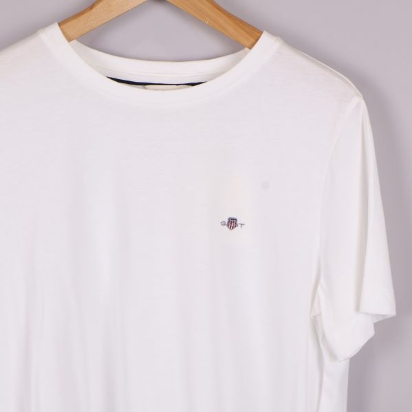 Framtill på vit t-shirt med broderad liten logotyp
