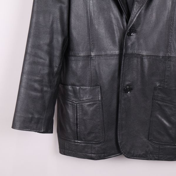 Detaljbild på nedre delen av svart skinnkavaj med ficka