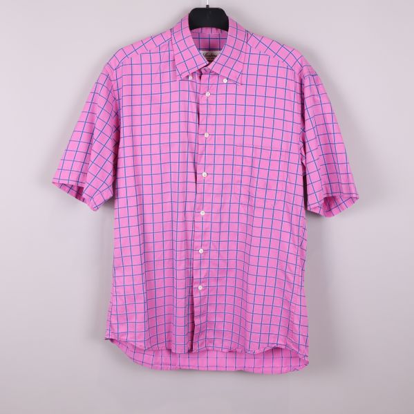 Kortärmad rosa skjorta med blåa rutor hängande på galge