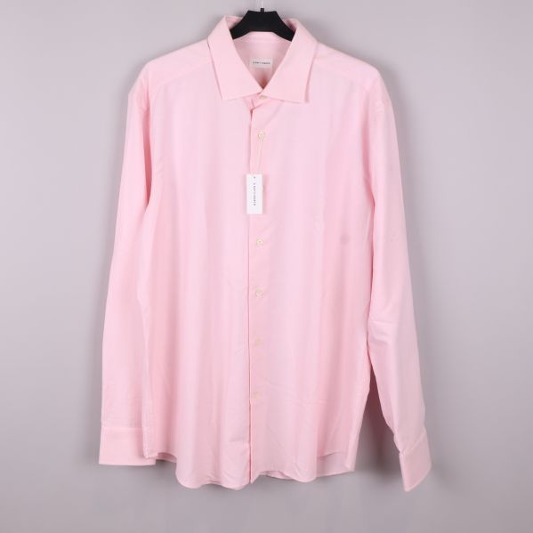 Ljusrosa skjorta på galge mot ljus bakgrund