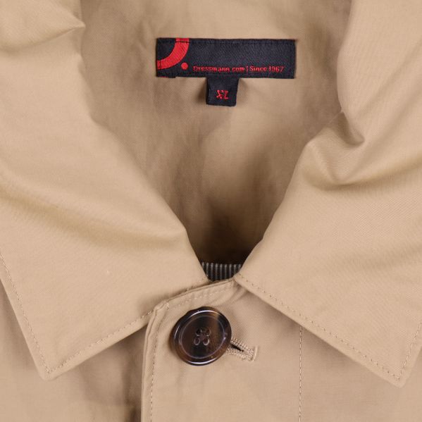 Närbild på krage och knapp i beige trenchcoat