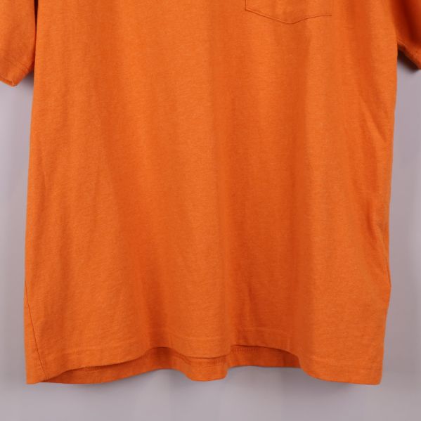 Nederkant på orange t-shirt visas i detalj