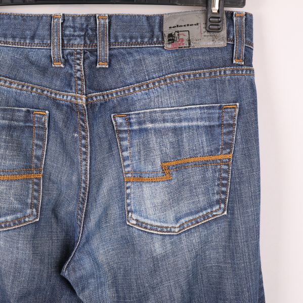 Närbild på bakfickor med tydliga kontrastsömmar på jeans
