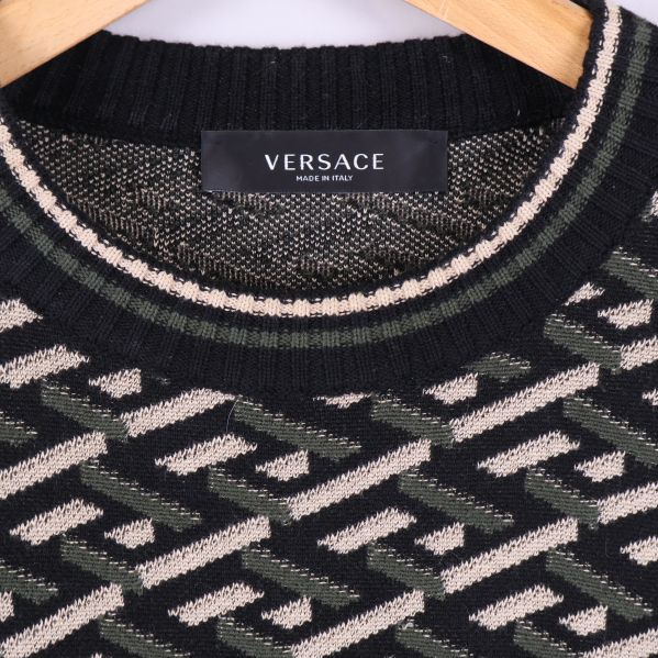 Närbild på Versace-logotyp vid kragen och stickat mönster