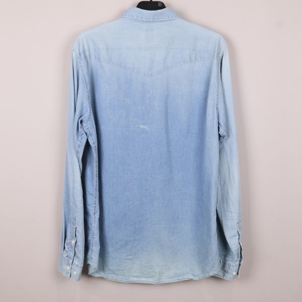 Baksida på ljusröd jeansskjorta med slitningar