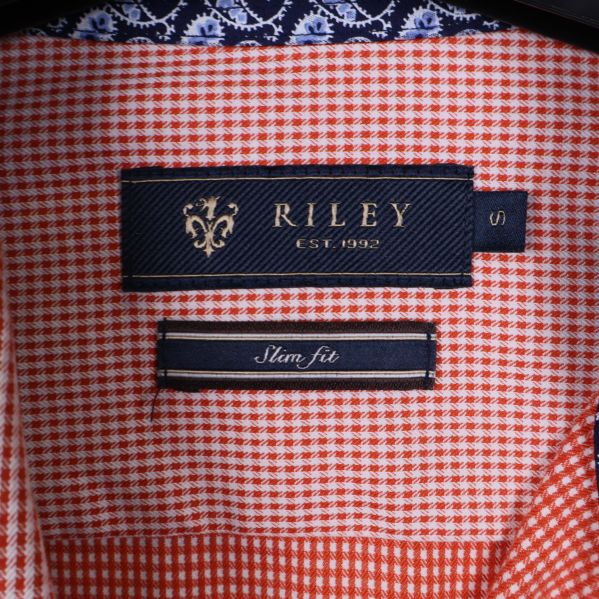 Närbild på Riley-logotyp och slim fit-etikett i kragen