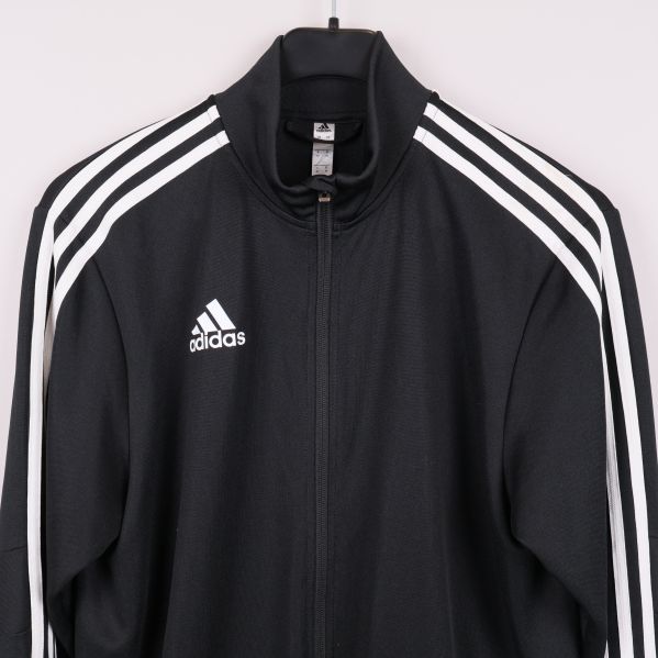 Närbild bröst på svart Adidasjacka med logga