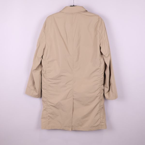 Baksidan på beige trenchcoat hänger på galge