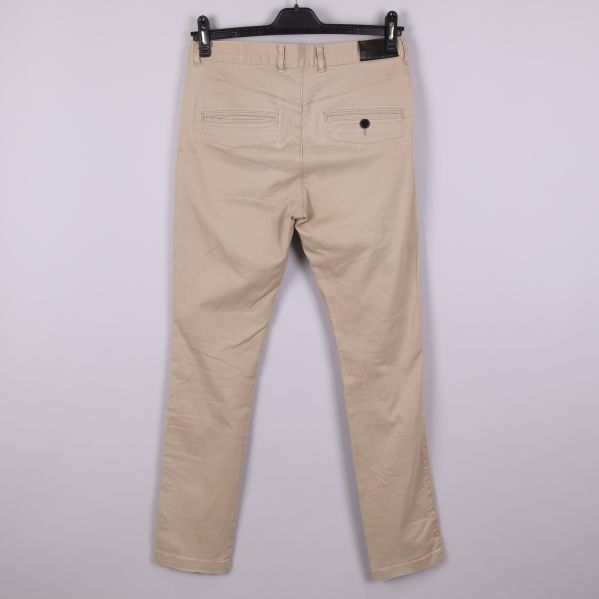 Baksidan av beiga chinos med släta passpoalfickor