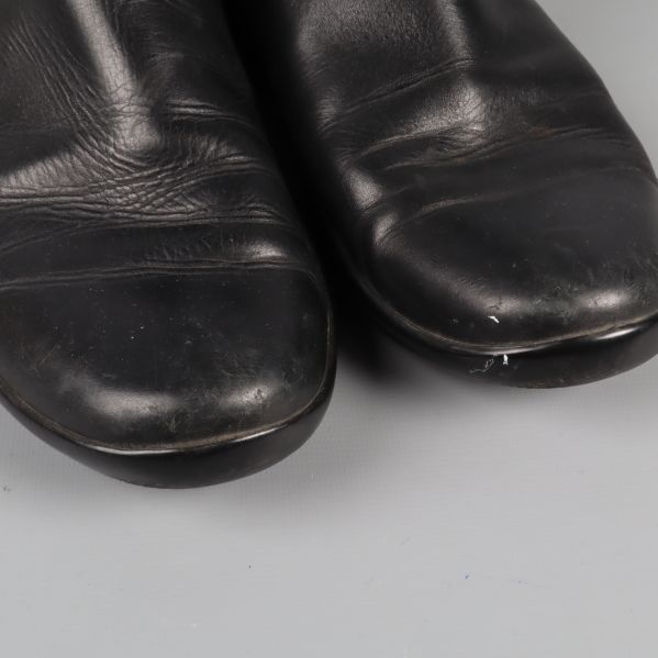 Närbild av tån på svarta boots med synligt slitage
