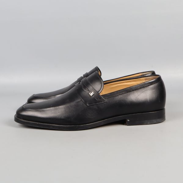 Svarta loafers fotograferade från sidan på ljus bakgrund