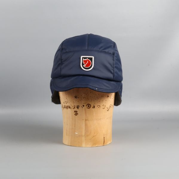 Blå vadderad keps med öronlappar sedd framifrån med logga