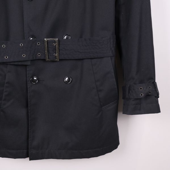 Detaljbild på ficka och ärmslut med spänne på trenchcoat
