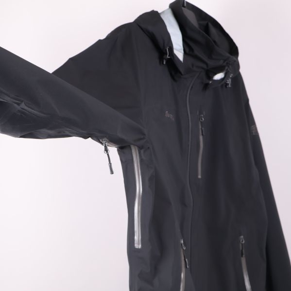 Närbild på svart jacka med ärmen utsträckt och ficka