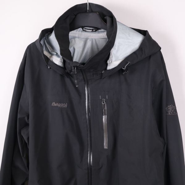 Närbild på jackans bröstdel med logga och huva