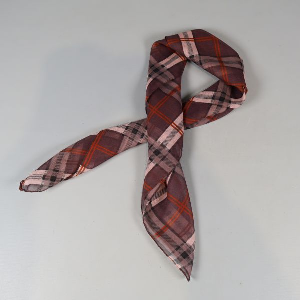 Rutigt scarf i rött och rosa, enkel knut på ljus bakgrund