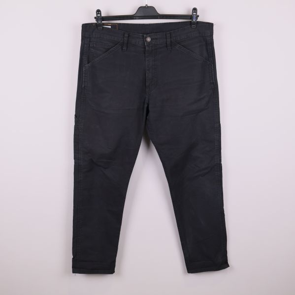 Framsida av svarta arbetsinspirerade jeans på galge