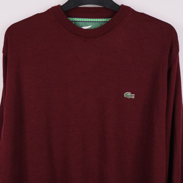 Närbild av bröstpartiet och Lacoste-märket på vinröd tröja