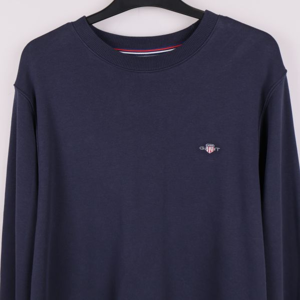 Närbild av logotyp på bröstet på marinblå sweatshirt