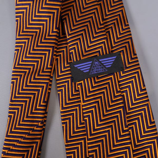 Närbild på etikett med lila logga mot zigzagmönster