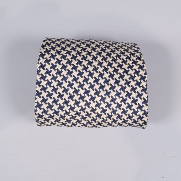 Närbild på slipsen rullad med hundtandsmönster i svart och beige