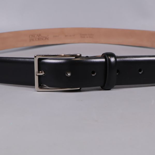 Närbild på spänne och hål av svart skärp i läder