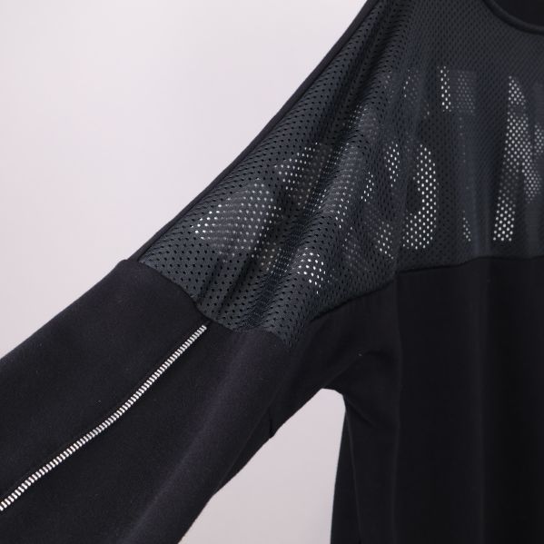 Närbild på ärm med reflekterande dragkedja och meshdetalj