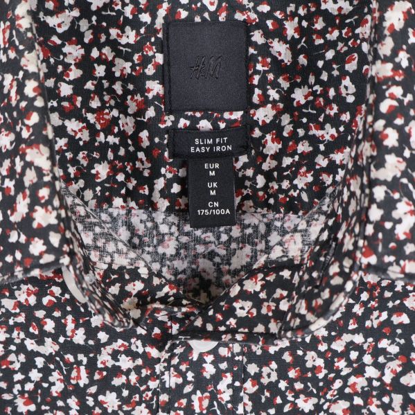 Detaljbild på H&M etikett och storlek i blommig skjorta