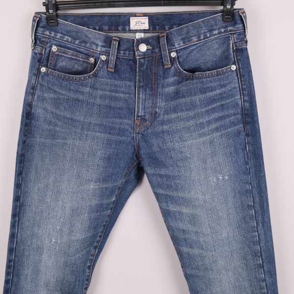 Närbild på framsida av blå jeans med subtila slitningar
