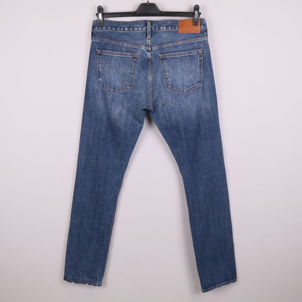 Baksida av blå jeans med två bakfickor och läderpatch